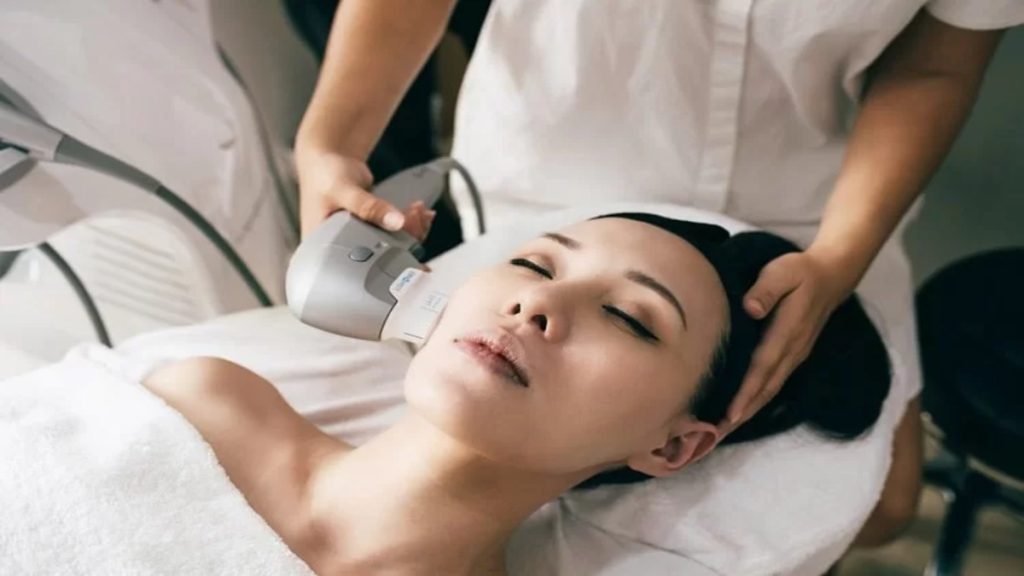 متخصص در حال انجام روش هایفوتراپی بر روی صورت یک خانم