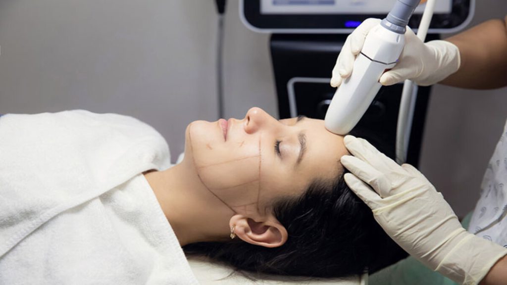 پزشک در حال انجام هایفوتراپی موی یک خانم می باشد پزشک در حال انجام هایفوتراپی موی یک خانم می باشد