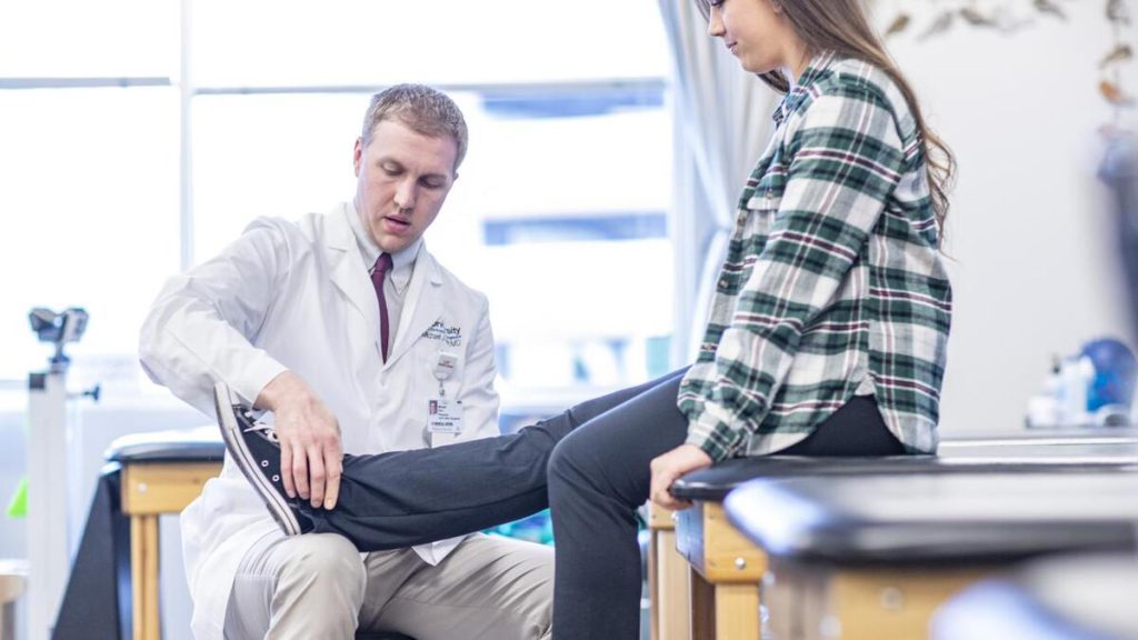 پزشک در حال معاینه خانمی که زانو درد دارد پزشک در حال معاینه خانمی که زانو درد دارد