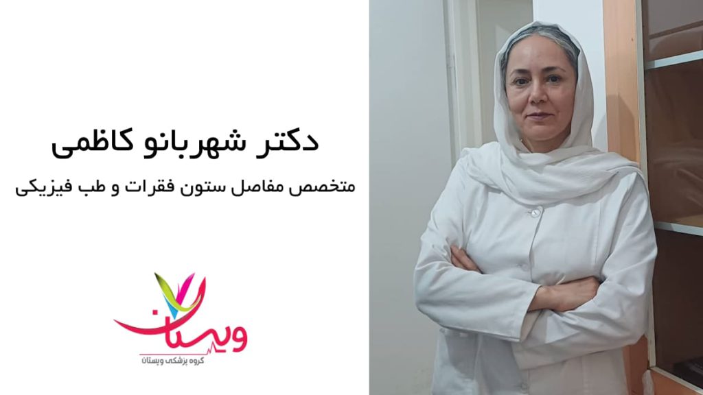 دکتر شهربانو کاظمی ایستاده در محیط درمانی دکتر شهربانو کاظمی با روپوش سفید و دستان بسته مقابل قفسههای پزشکی ایستاده است
