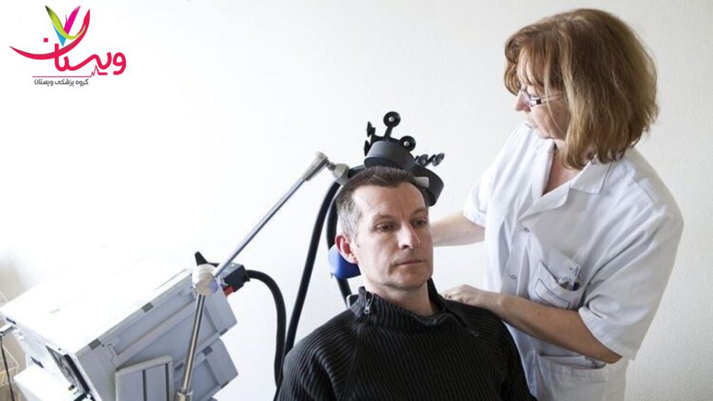 تنظیم موقعیت دستگاه آر تی ام اس توسط پزشک پزشک در حال قرار دادن دستگاه آر تی ام اس روی سر بیمار برای آغاز درمان اضطراب و استرس است